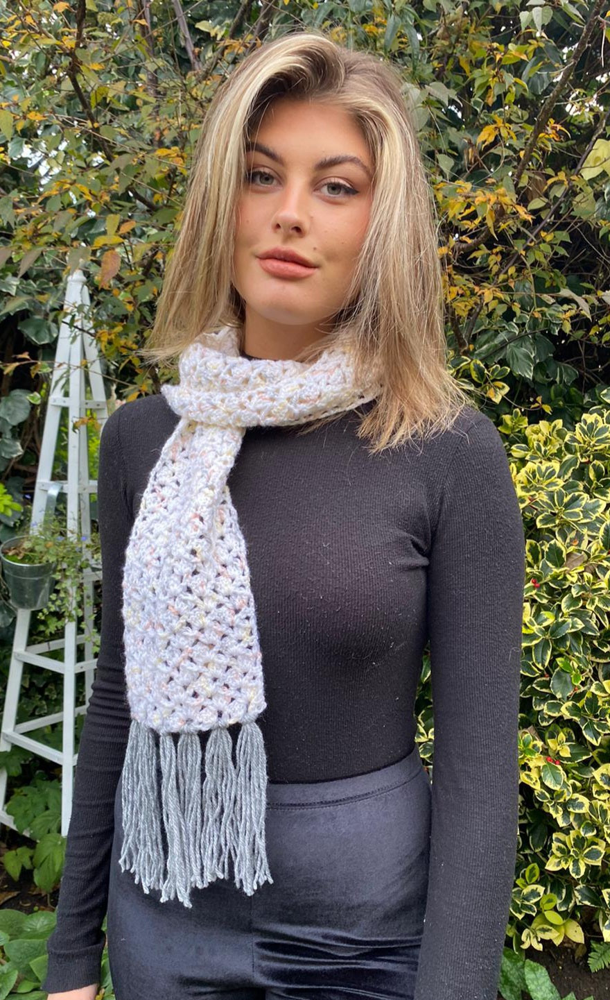 Pretty open-textured tasselled cream scarf with splashes of apricot & grey.