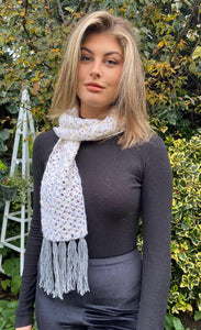 Pretty open-textured tasselled cream scarf with splashes of apricot & grey.