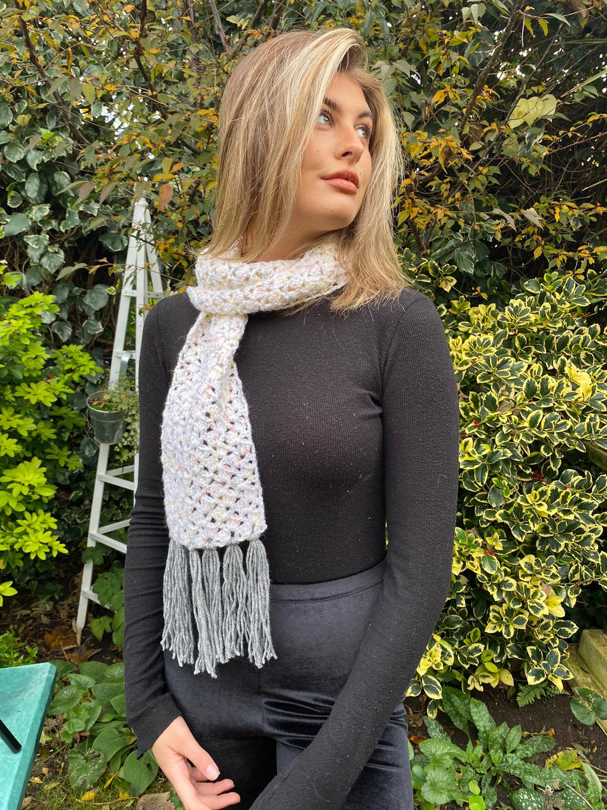 Pretty open-textured tasselled cream scarf with splashes of apricot & grey.